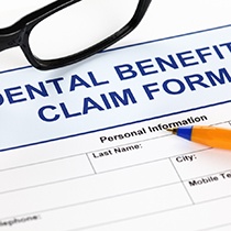 Dental benefits claim form, glasses, and pen