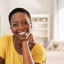 Woman in yellow shirt smiling in living room
