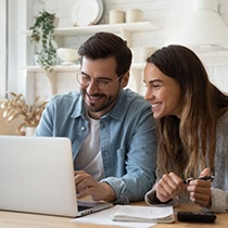 Two people looking at a laptop to learn more about dental insurance