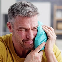 Man putting ice on his cheek