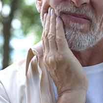 a man holding his jaw due to failed dental implant