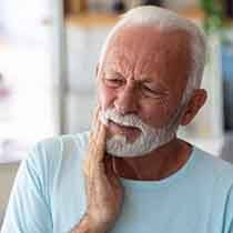 a man touching his jaw due to tooth pain