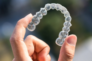 Close up of someone holding a pristine Invisalign tray